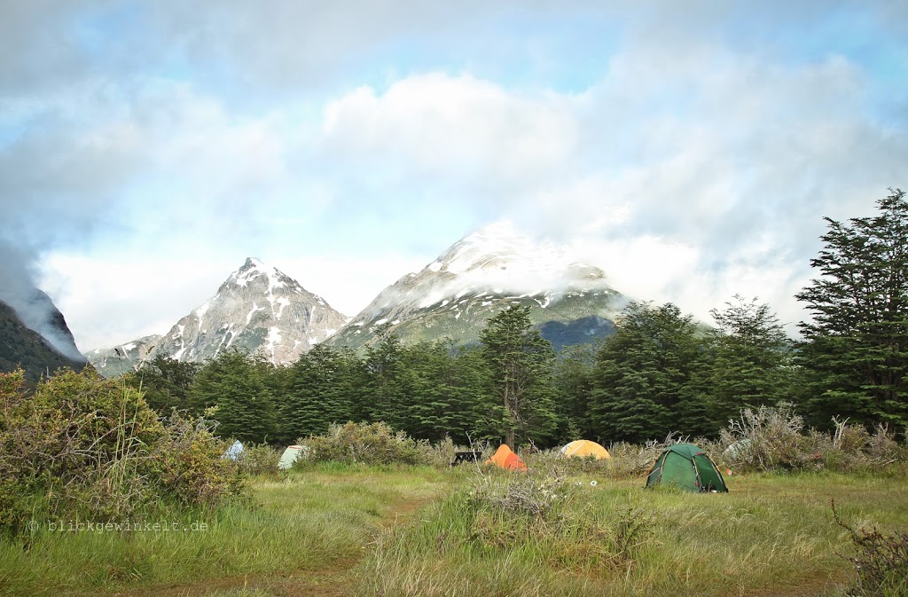Zelte auf Wiesen, schneebedeckte Berge im Hintergrund
