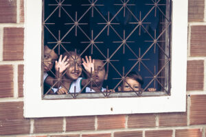 Kinder gucken aus vergittertem Fenster