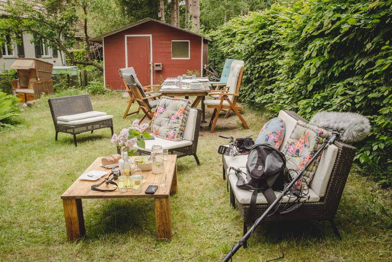 Gartenmöbel mit bunten Kissen und Holztisch und Gartenhaus