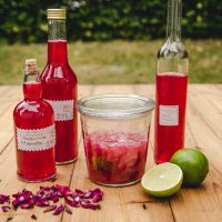 Rosenblütenwasser und Rosenblütensirup, Flaschen auf Holztisch