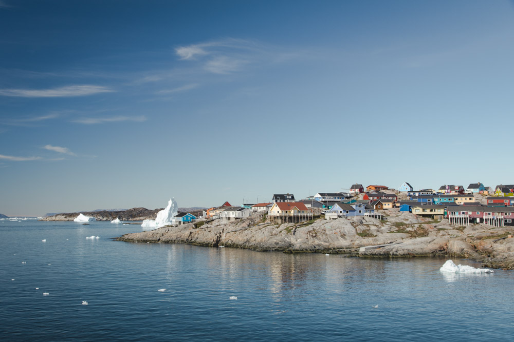 Bunte Häuser am Fjord mit Eisbergen