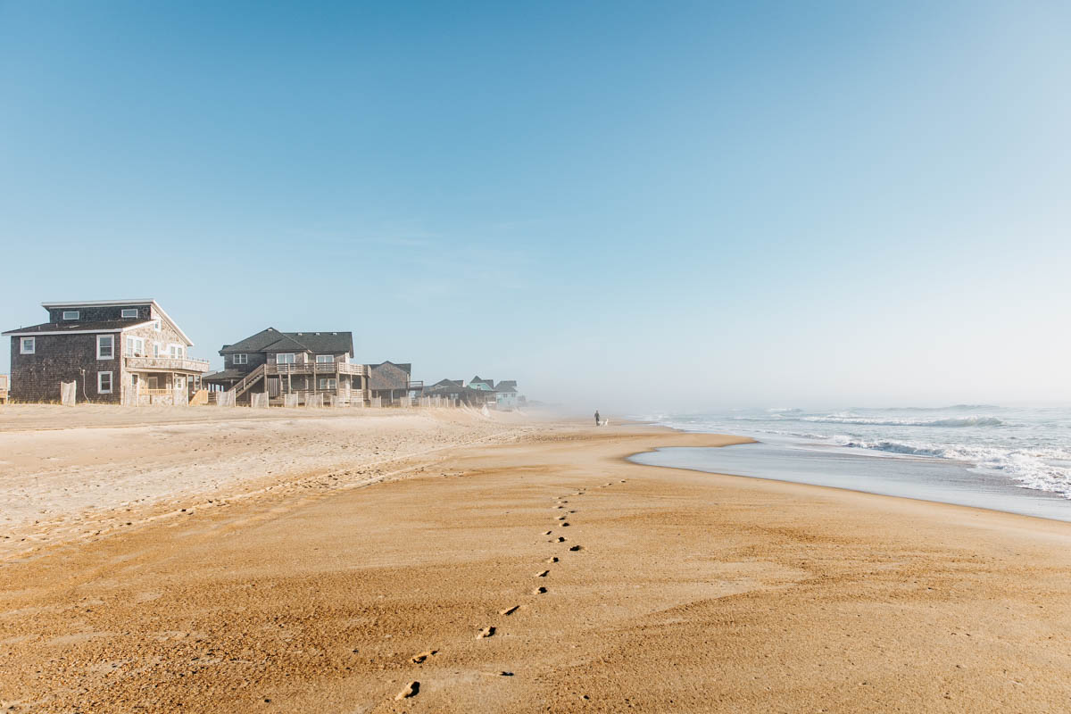 Strand mit Häusern und Fußspuren