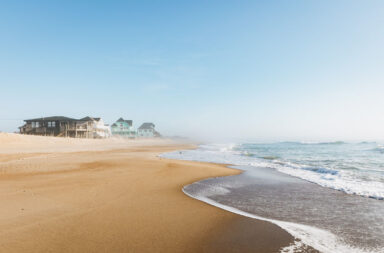 Strand mit Häusern im Nebel