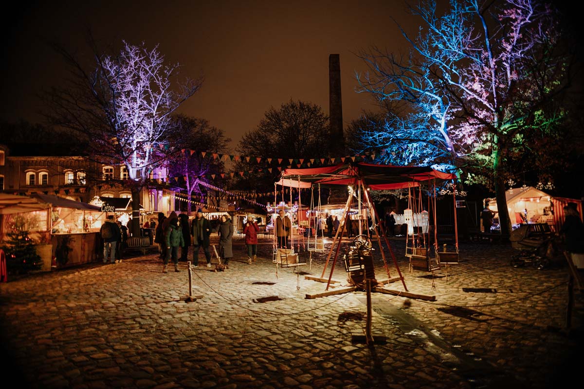 gepflasterter Schlossplatz mit altem Karussel, Lichtern und Weihnachtsbuden